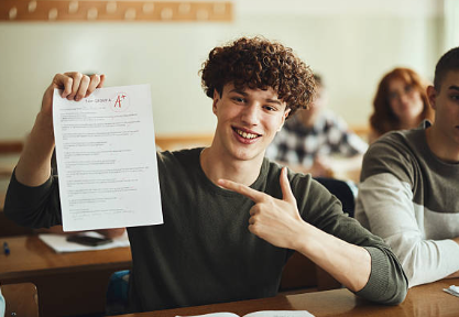 High school student proudly showing an A plus on schoolwork